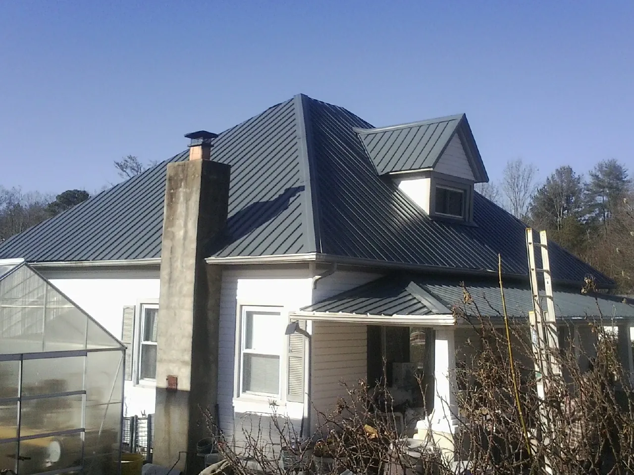 Dark blue standing seam metal roof on a white farmhouse with dormer — Slate & Tile Roof Repair by Roofing Brothers in Mira Loma