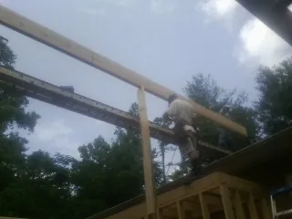 Carpenter setting a ridge beam over a new addition frame in Mira Loma