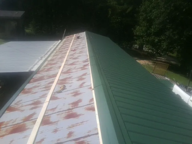 Old rusted panels beside newly installed green metal roofing — Wind Damage Roof Repair by Roofing Brothers in Mira Loma