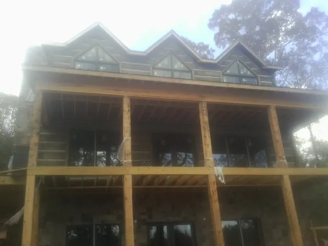 Dormers and porch framing on a large log home under construction — Roof Coating work by our crew in Mira Loma