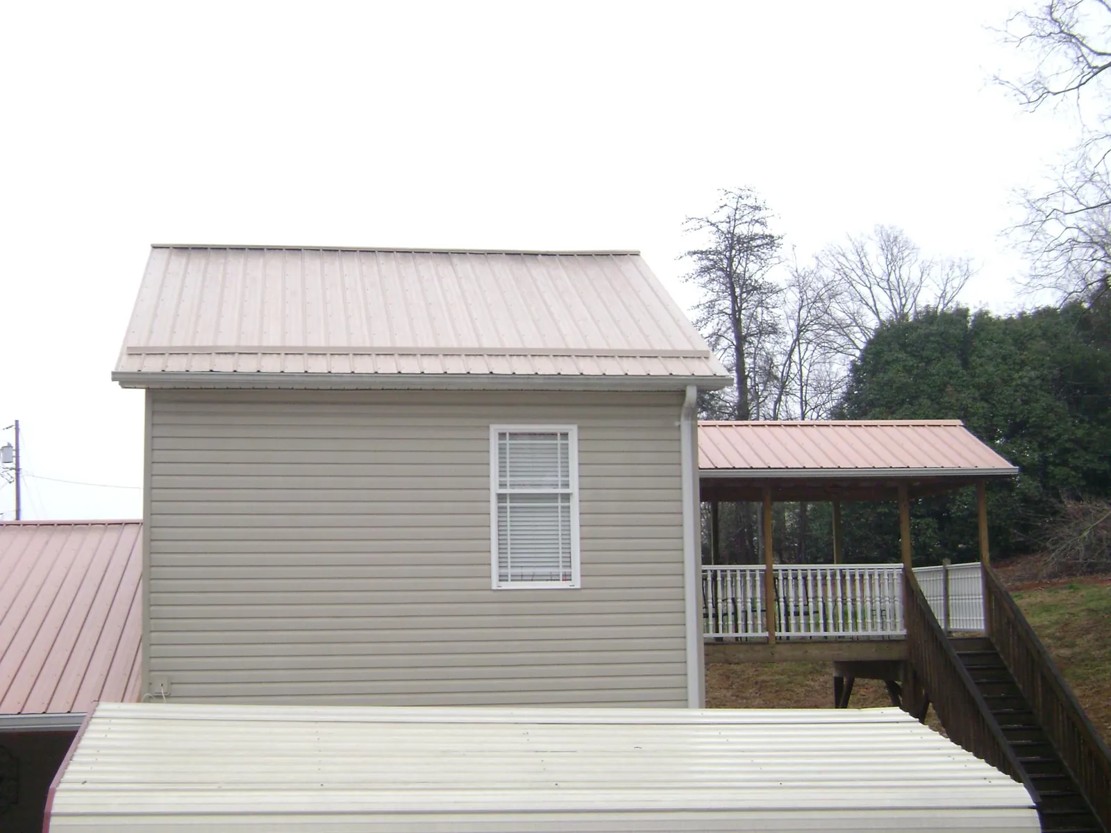 Tan metal roofs on a two story addition and attached porch, from a Roof Replacement job in Mira Loma