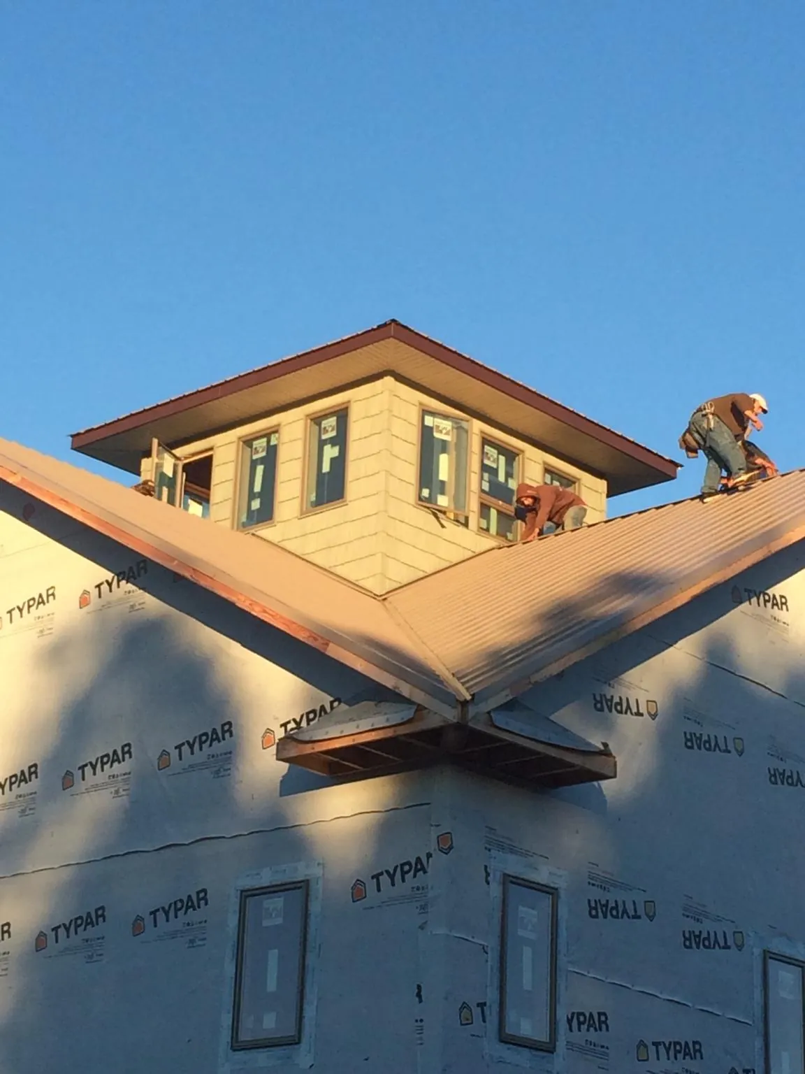 Roofers working around a rooftop cupola on a new metal roof at sunset — Roof Waterproofing in Mira Loma by Roofing Brothers